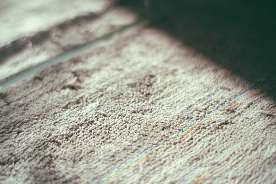 Close-up view of a vacuum cleaner with a transparent dirt collection canister filled with dust and debris, connected to a flexible hose and a wide attachment for surface cleaning. The vacuum is positi